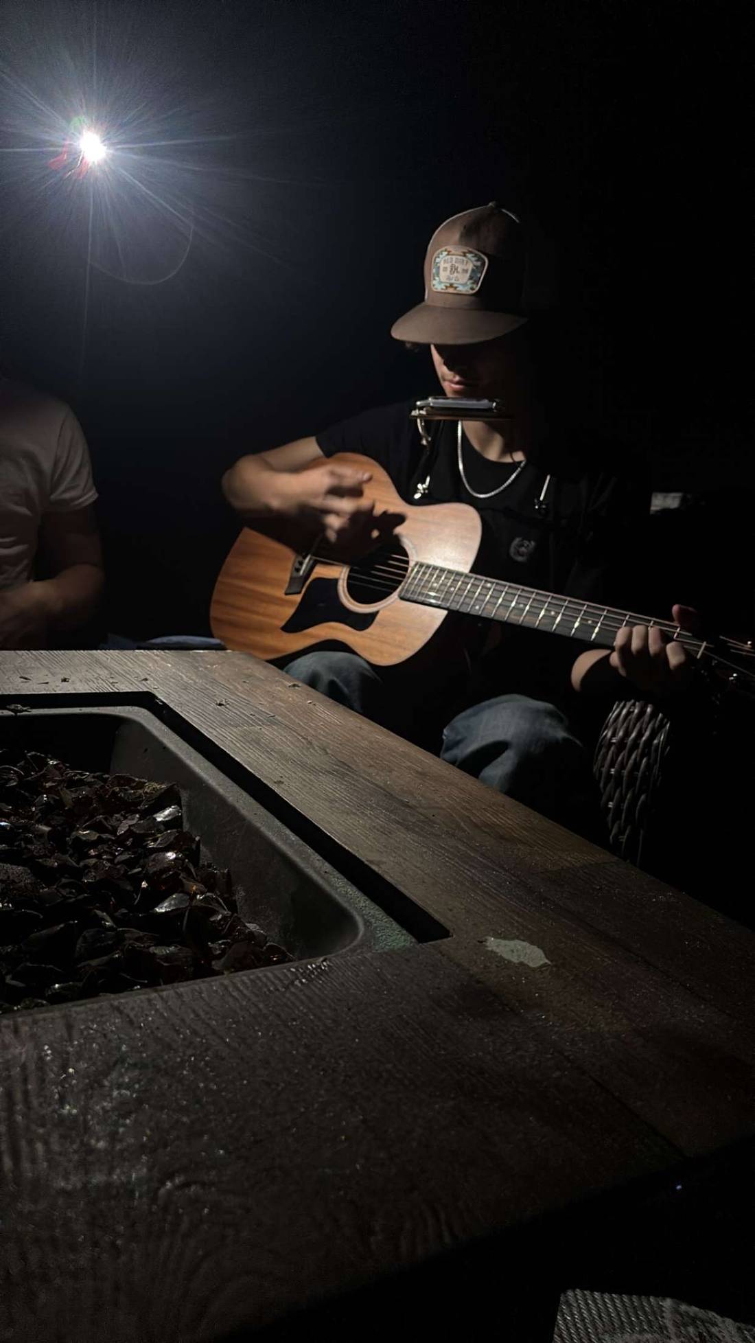 Matteo playing guitar and harmonica by the fire